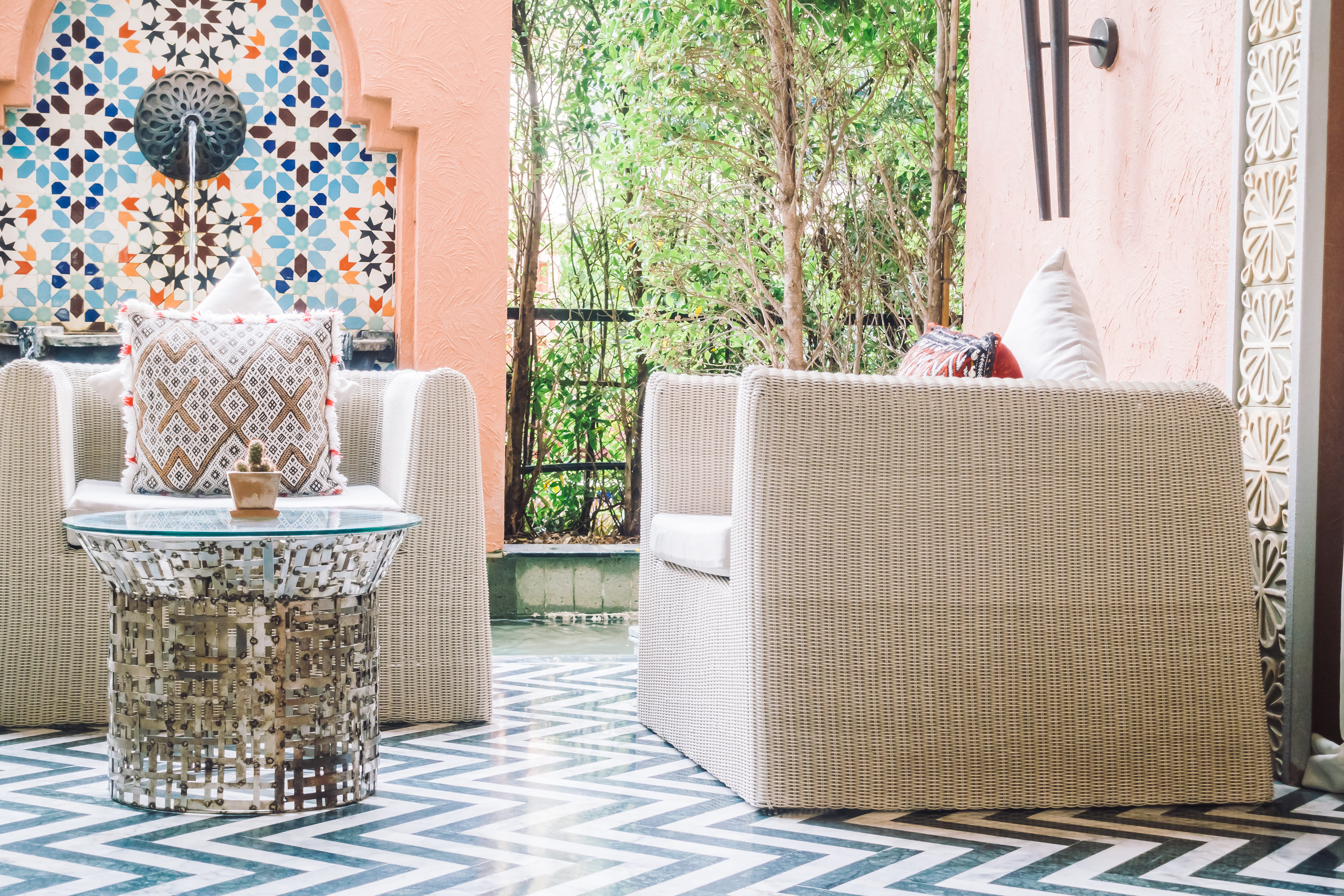 Elegant riad terrace lounge with Moroccan zellige floor and carved plasterwork screen in Marrakech